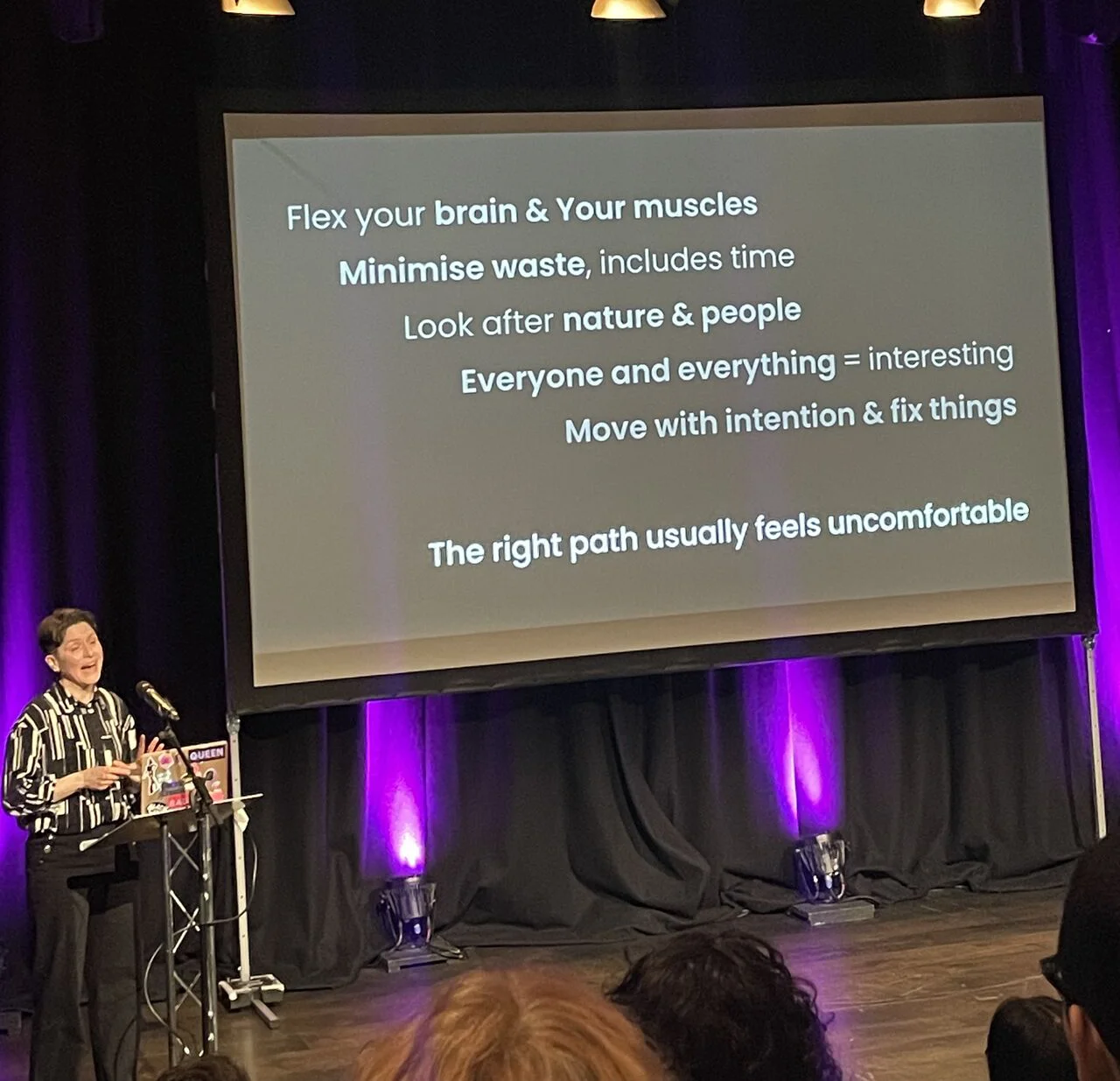 Fiona MacNeill is speaking at the front of the room, the slide on the screen featured text included below the image.